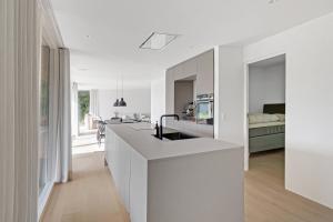 a white kitchen with a sink and a living room at Holiday Home On Bornholm Close To Sea And Beach in Vester Sømarken +19 photos