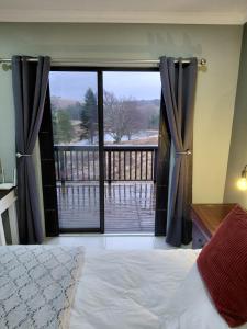a bedroom with a large window with a view of a balcony at Underwood Country Manor in Underberg