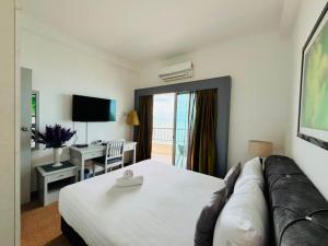 a hotel room with a bed and a desk and a television at Rainbow Paradise Seaview by Achlys Collection in Tanjung Bungah