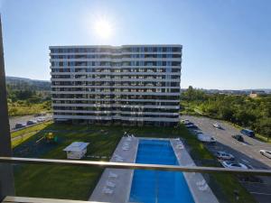 a large building with a pool in front of a parking lot at Pool View Apartment Varna in Varna City