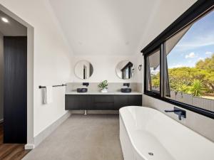 a bathroom with a white tub and a large window at Stone River Villa 2 - Private Escape - Heated Pool in Margaret River Town +9 photos