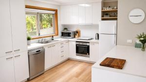 a white kitchen with white cabinets and appliances at Coastal Cottage in Saint Leonards