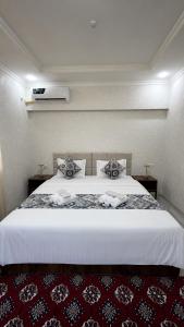 a bedroom with a large white bed with a red carpet at Abuzar in Bukhara