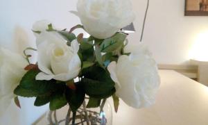 a vase filled with white roses sitting on a table at B&B Salviani in Acilia