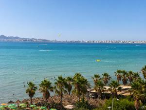 a beach with palm trees and people in the water at Bedo Boutique Hotel in Golem