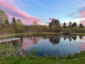 a lake with a wooden dock in the middle at The Evergreen | Walk to Rangeley Lake, Sled & ATV Access in Rangeley +4 photos