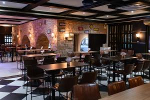 a restaurant with tables and chairs and a brick wall at Kiss Gardenhome Chic Hotel in Hat Yai
