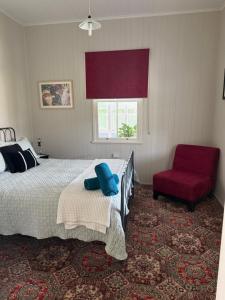 a bedroom with a bed and a red chair at Finney Cottage in Stanthorpe