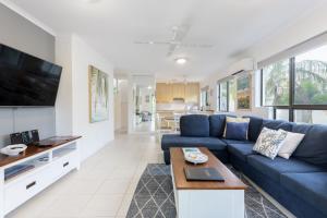 a living room with a blue couch and a tv at Seascape Holidays - Tropical Reef Apartments in Port Douglas