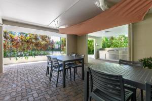 a patio with a table and chairs and a kitchen at Seascape Holidays - Tropical Reef Apartments in Port Douglas