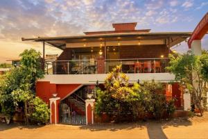 a building with a balcony with tables and chairs at Green Woods Cottage by JN in Mahabaleshwar +12 photos