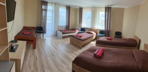 a room with three beds and a living room with windows at Babilonas in Plungė