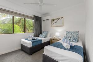 a bedroom with two beds and a window at Seascape Holidays - Tropical Reef Apartments in Port Douglas +22 photos