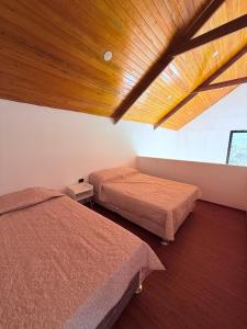 a bedroom with two beds and a wooden ceiling at Villa Doña Isabel in Lunahuaná +18 photos