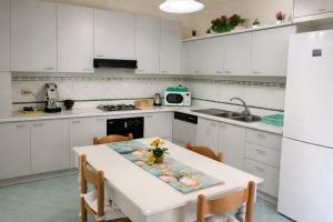 a kitchen with white cabinets and a table with chairs at Fardella 75 in Trapani