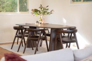a dining room table with chairs and a vase with a plant at Sunset Palms in Smiths Lake