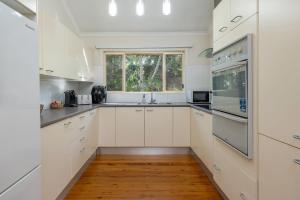 a kitchen with white cabinets and a window at Sunset Palms in Smiths Lake