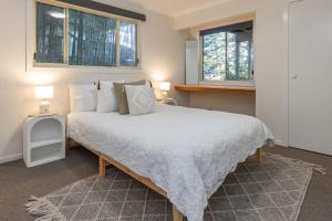 a bedroom with a large white bed with two windows at Sunset Palms in Smiths Lake