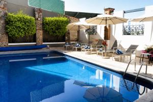 a swimming pool with chairs and umbrellas at Hotel Borda Cuernavaca in Cuernavaca
