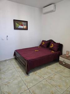 a bedroom with a bed with purple sheets and a picture on the wall at Hot Payton in Mamoudzou