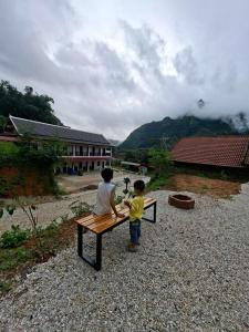two young boys sitting on a bench in a field at Sokmoungkhoun in Nongkhiaw +2 photos