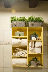 une étagère jaune avec des serviettes et des plantes dans la salle de bains dans l'établissement Casa Torrazzo, à Pisogne