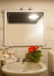 La salle de bains est pourvue d'un lavabo avec miroir et d'une fleur rouge. dans l'établissement Casa Torrazzo, à Pisogne