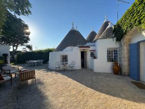 a white house with a patio with chairs and tables at I Trulli di Federico in Selva di Fasano