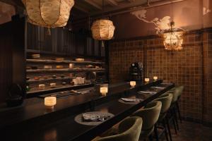 a restaurant with a long bar with chairs and lights at Chicago Athletic Association, part of Hyatt in Chicago