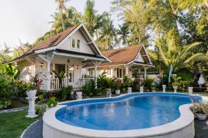 a villa with a swimming pool in front of a house at Jalana Palm Villa in Tabanan