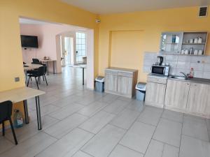 a kitchen with yellow walls and a white tile floor at Babilonas in Plungė