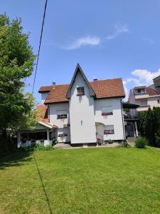 a large white house with a grass yard at Kuća JEKA in Vrnjačka Banja