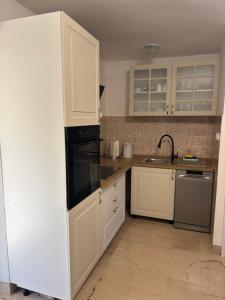 a kitchen with white cabinets and a black appliance at Kameni cvijet in Murvica +12 photos
