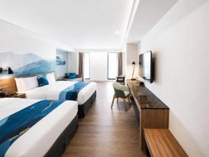 a hotel room with two beds and a desk at Just Sleep Hualien ZhongZheng in Hualien City