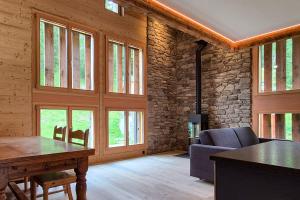 a living room with a table and chairs and windows at Chalet Nufenen in Ulrichen