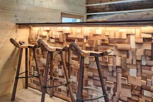 a wall of reclaimed wood with two stools in front of it at Chalet Nufenen in Ulrichen