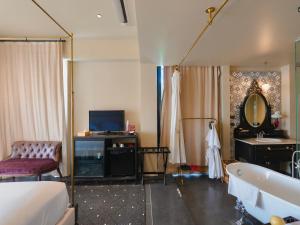 a bedroom with a bed and a tub and a television at Amdaeng Bangkok Riverside Hotel in Bangkok