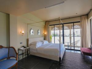 a bedroom with a canopy bed and a balcony at Amdaeng Bangkok Riverside Hotel in Bangkok +115 photos