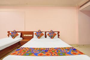 a bedroom with two beds with colorful pillows at FabHotel Vaishanvi Palace in Hyderabad