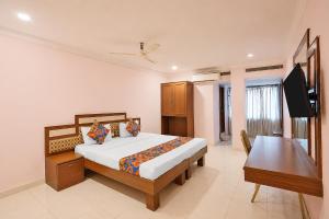 a bedroom with a bed and a desk and a television at FabHotel Vaishanvi Palace in Hyderabad
