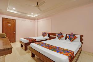 a bedroom with two beds and a table and a desk at FabHotel Vaishanvi Palace in Hyderabad