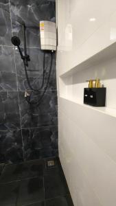 a shower in a bathroom with a black and white wall at Ladda Garden Home in Klong Muang Beach