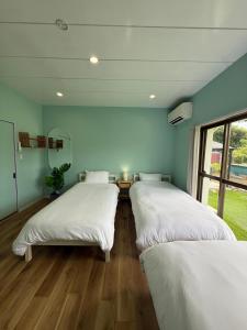 two beds in a room with blue walls and wooden floors at Yumigahama Eaglehouse 2 in Minamiizu