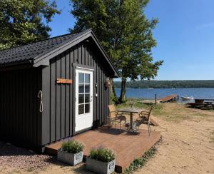 a black shed with a table and chairs on a deck at Vånga 771 in Örkelsö