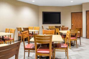 a dining room with tables and chairs and a flat screen tv at Econo Lodge Ankeny - Des Moines in Ankeny