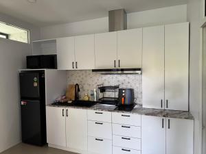 a kitchen with white cabinets and a black refrigerator at Silver Palm Tree Villa - 2 Bedrooms Villa in Ao Nang Beach