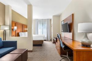 a hotel room with a bed and a desk with a computer at Comfort Suites Greensboro-High Point in Greensboro