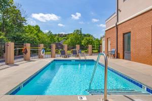 a swimming pool with chairs and a brick building at Comfort Suites Greensboro-High Point in Greensboro