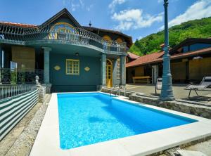 a blue swimming pool in front of a house at Requiem Rustical Heaven Villa with Outdoor Pool in Varaždin