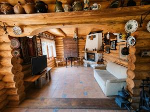a living room in a log cabin with a couch and a tv at Traditional wooden cottage in Cîmpu Cetăţii